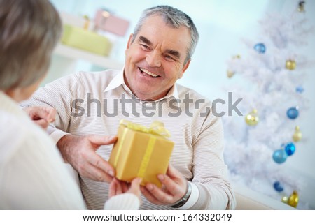 Portrait of mature man giving Christmas present in box to his wife