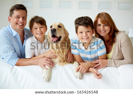 Portrait Of Happy Family With Their Pet Looking At Camera