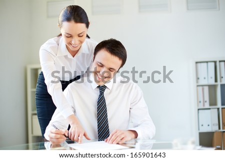 Portrait of businessman going to sign agreement while his secretary showing him where to sign