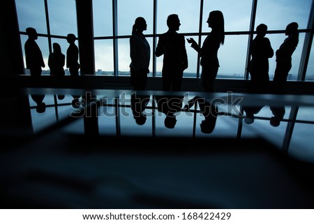 Silhouettes Of Several Colleagues Communicating In Office