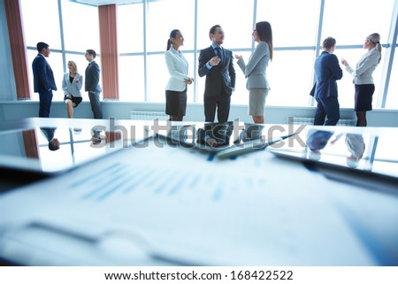Business people interacting in office with workplace in front of them