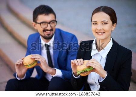 Businesswoman and her colleague eating sandwiches outside