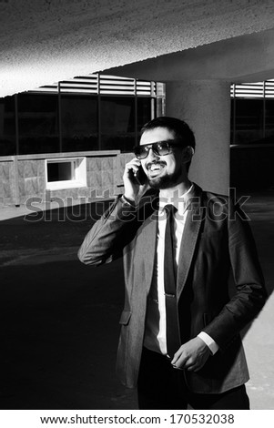 Black-and-white image of a smiling businessman speaking on the phone outside