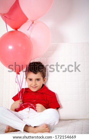 Portrait of happy lad with balloons relaxing on sofa