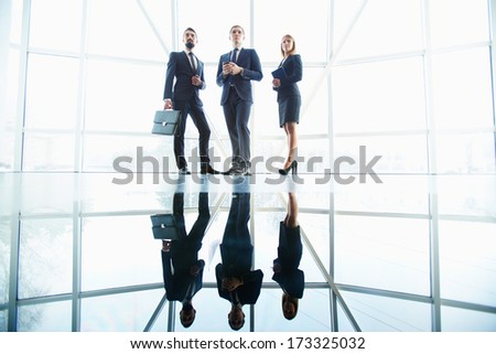 Outlines of successful business partners standing against window in office building
