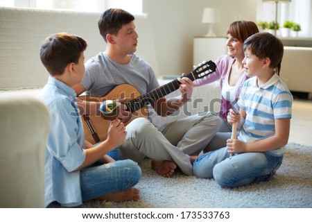 Portrait of handsome siblings and their father playing musical instruments at home