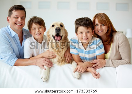 Portrait Of Happy Family With Their Pet Looking At Camera