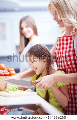 Portrait of happy mother and two daughters cooking in the kitchen
