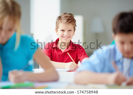 Portrait of cute schoolboy looking at camera at drawing lesson