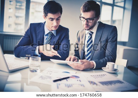 Image of two young businessmen discussing new project in office