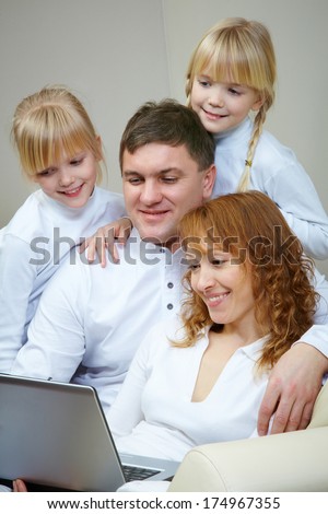 Image of friendly family watching film by laptop