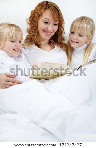 Portrait of mother reading to her daughters before sleep