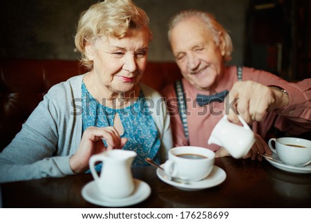 Portrait of retired couple in smart clothes having tea in cafe