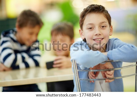 Positive boy sitting in cafe with his friends