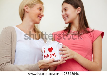 Teenage girl holding giftbox and giving it to her mom