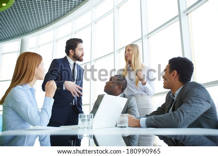 Group of business partners looking at their boss explaining his idea to employee