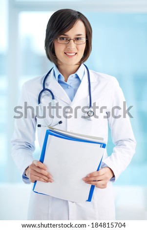 Vertical portrait of a lovely general practitioner holding documents