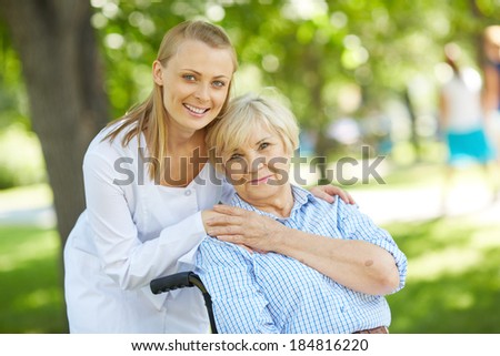 Pretty nurse and senior patient looking at camera outside