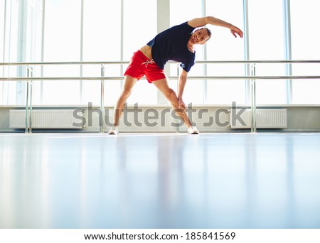 Portrait of happy young man doing physical exercise in gym