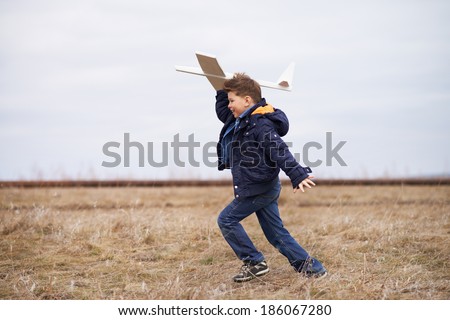 Photo of happy kid playing with toy airplane outside