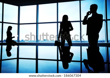 Silhouettes of several office workers working in office