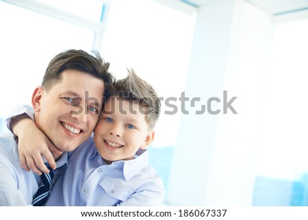 Photo of happy man and his son embracing and looking at camera