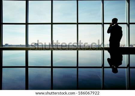 Outline of office worker speaking on the phone by the window Outline of office worker speaking on the phone by the window