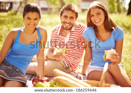 Group of young friends eating sandwiches at picnic in the country