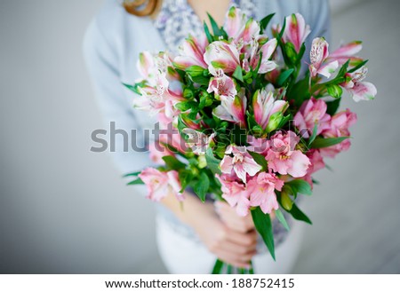 Close-up of bunch of pink lilies held by female