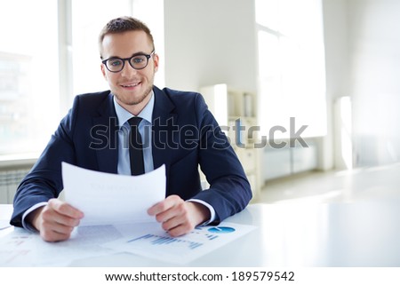 Portrait of smiling employee with paper looking at camera in office