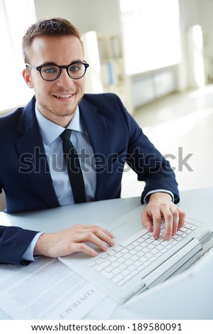 Portrait of smiling employee with laptop looking at camera in office