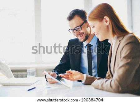Image of two young business partners using touchpad at meeting
