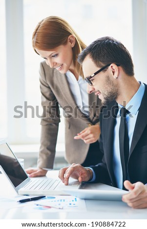 Image of two young business partners using laptop at meeting