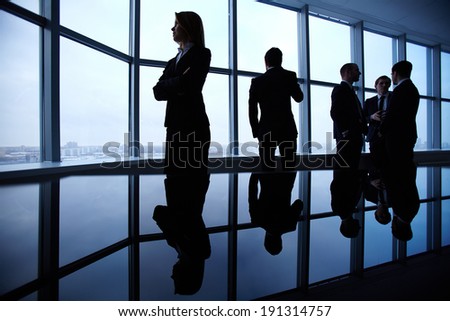 Group of colleagues standing along window in office