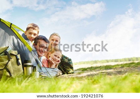 Portrait of family of travelers in tent looking at camera