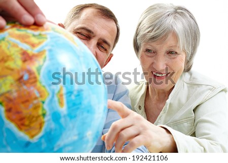 Portrait of happy senior couple looking at globe