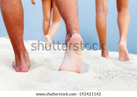 Soles of teenagers walking down sandy beach