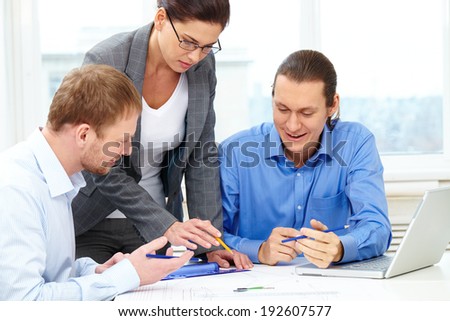 Three businesspeople sitting at table and discussing a project