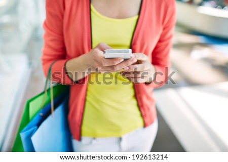 Female customer with cellular phone and shopping bags in the mall