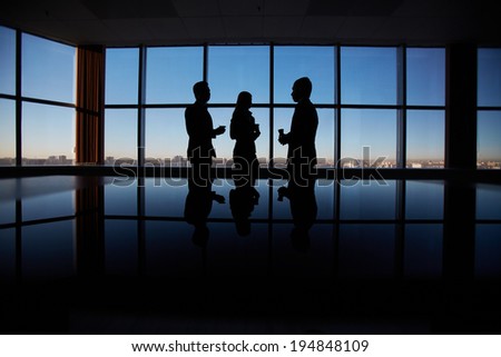 Outlines of group of white collar workers interacting by the window in office