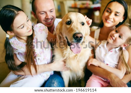 A young friendly family of four cuddling their pet