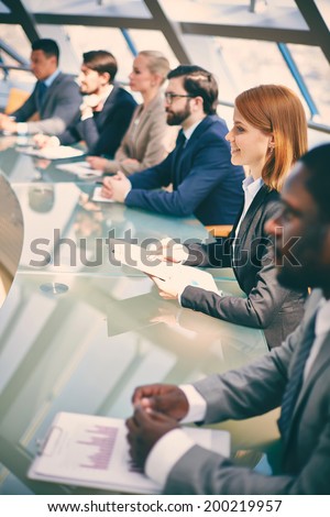 Row of business people listening to presentation at seminar with focus on smiling woman