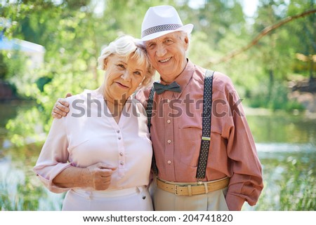 Happy seniors in smart casual looking at camera in park