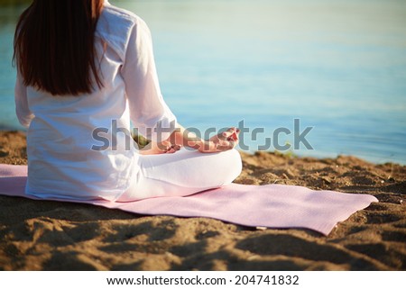 Back of meditating woman relaxing in pose of lotus outdoors