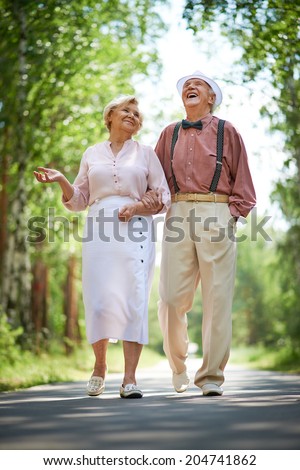 Happy seniors talking and having fun while taking a walk in the park