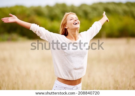 Image of happy woman with outstretched arms standing in field