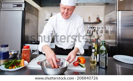 Image of male chef cooking meat in the kitchen