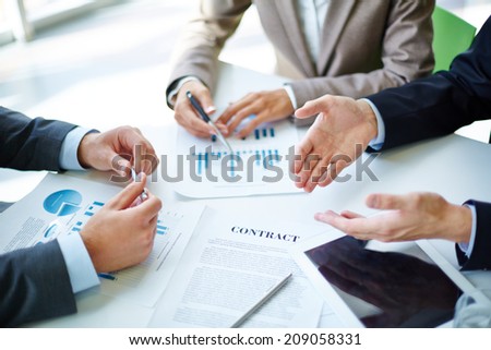 Image of business partners hands over business objects on workplace at meeting