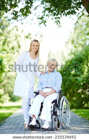 Pretty nurse taking care of senior patient while taking walk in park