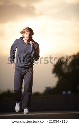 Portrait of young sportsman running outside